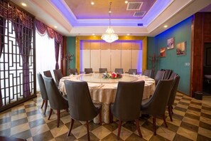 Un salón de conferencias con una mesa redonda, sillas y una lámpara de araña.