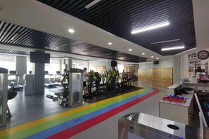 Un gimnasio con equipamiento de ejercicio, una pista de atletismo de colores del arcoíris y una pared con carteles motivacionales.