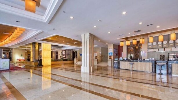 A spacious lobby with a polished marble floor, a reception area with a counter and seating, and a staircase leading to upper floors. - Huadong Hotel (Qitaihe (Xinjiang))