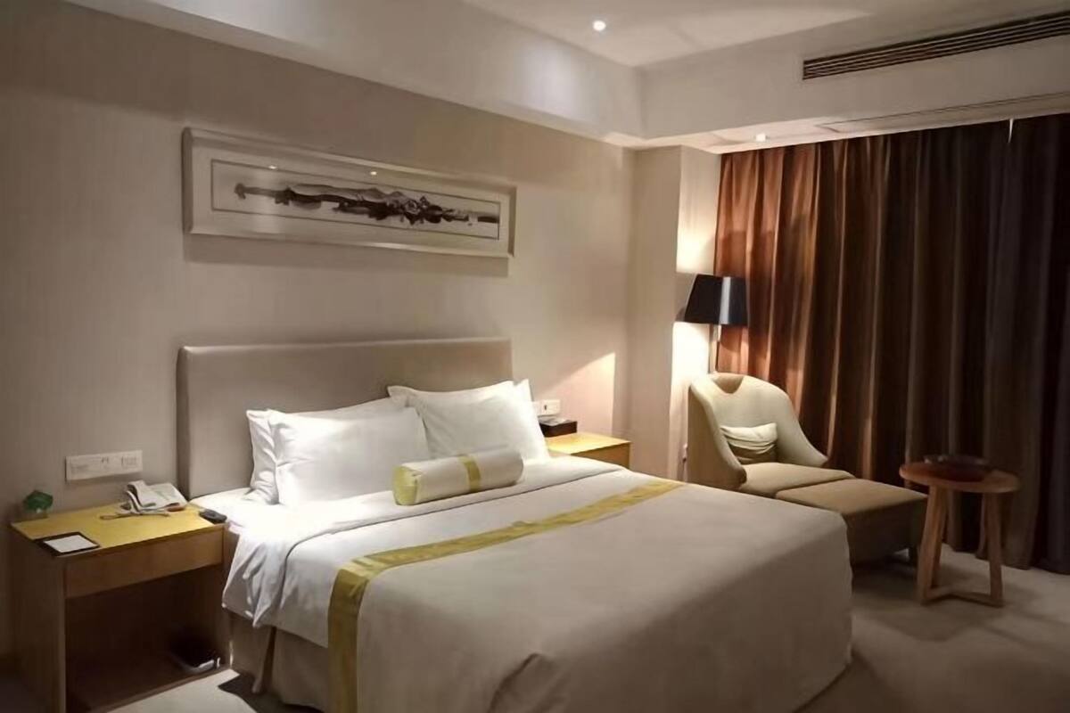 Une chambre d’hôtel avec un grand lit, une table de chevet, une lampe, une chaise et une petite table.
