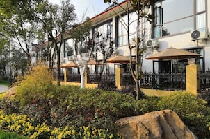 Un edificio con espacios de esparcimiento al aire libre, un sendero empedrado y un jardín ajardinado con diversas plantas.