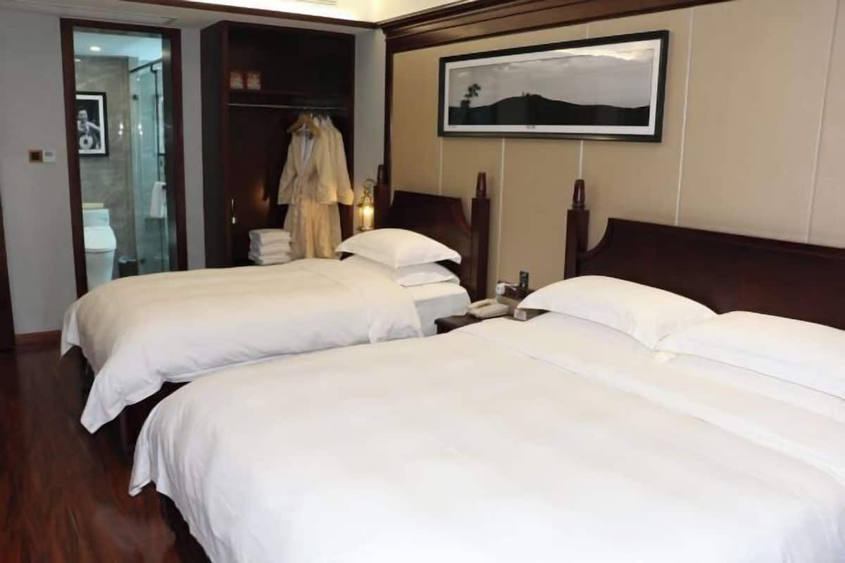 Habitación de hotel con dos camas, un armario, un baño y un cuadro en la pared.