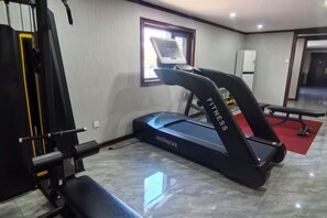 A gym with a treadmill, weight bench, and exercise equipment.