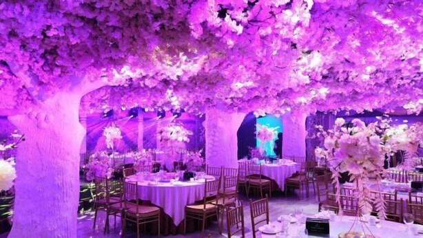Une salle de banquet avec des tables rondes, des chaises et des compositions florales.