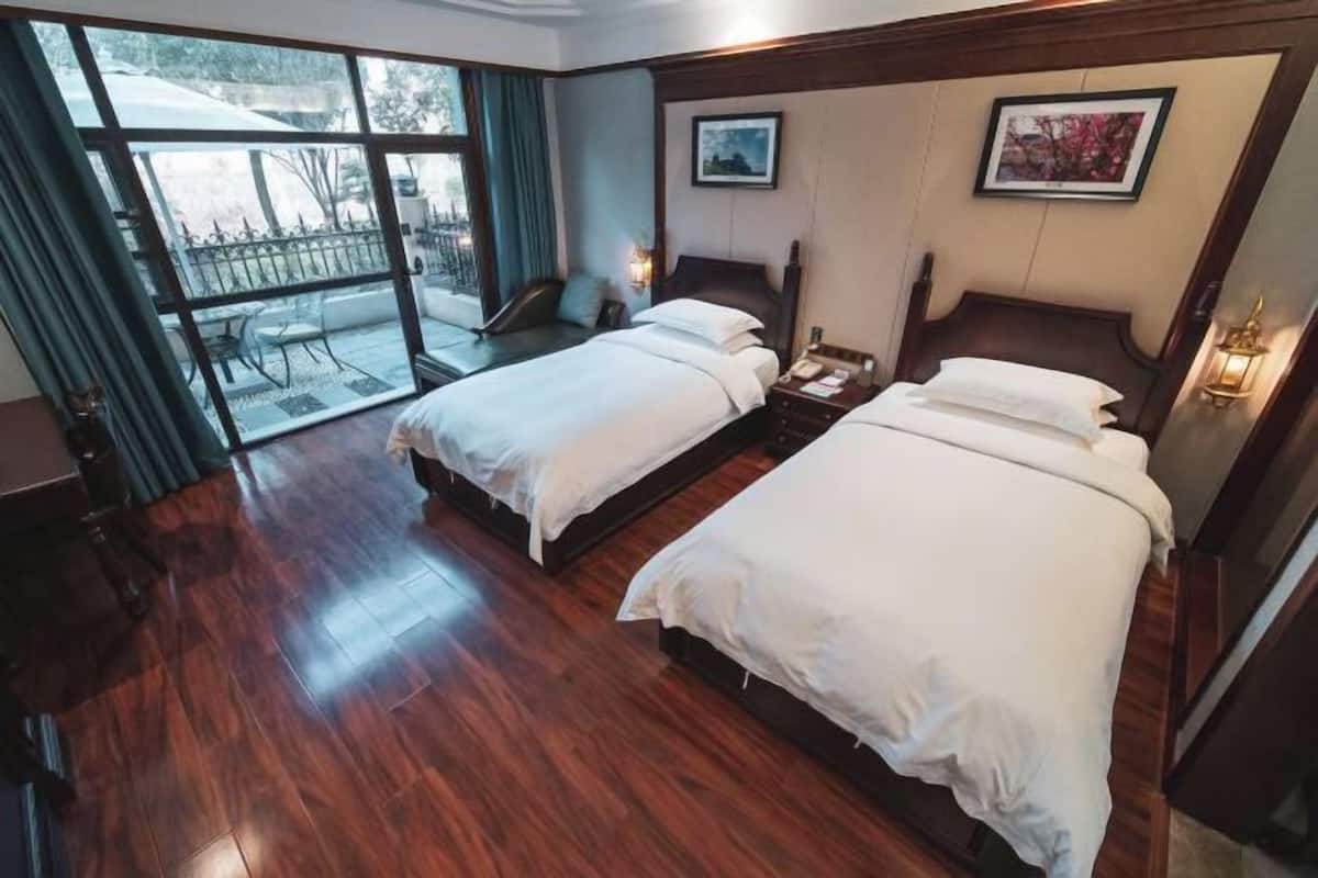 Habitación de hotel con dos camas, un ventanal grande y vistas al exterior.
