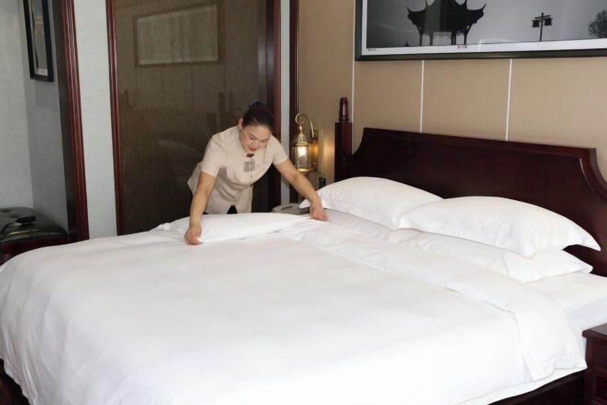 Ein ordentlich bezogenes Bett mit weißen Leinen in einem Hotelzimmer.