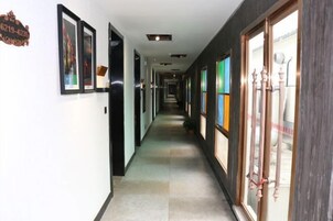 Un pasillo de hotel con cuadros enmarcados en las paredes, suelo de baldosas y una puerta con pomo decorativo.