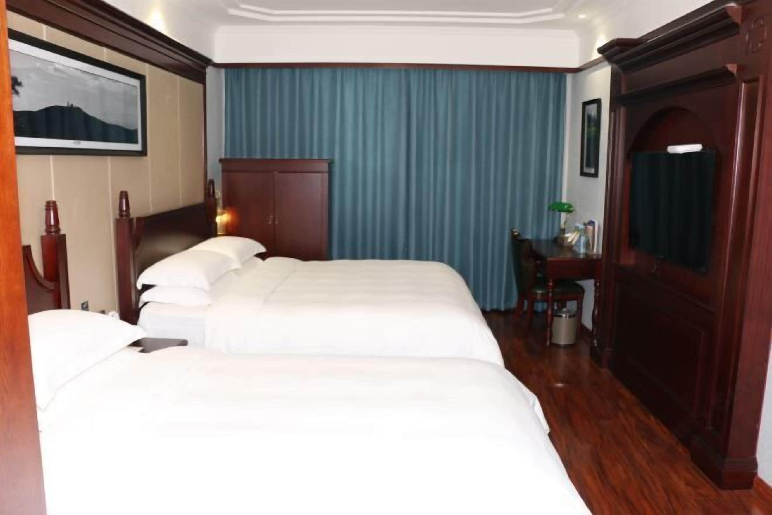 Ein Hotelzimmer mit einem großen Bett, einem Schreibtisch, einem Stuhl, einem Kleiderschrank und einem gerahmten Bild an der Wand.