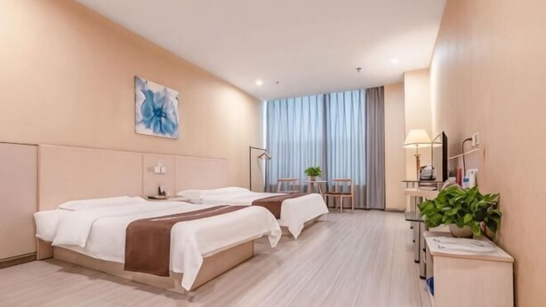 A hotel room with two beds, a desk with a lamp, a mirror, and a plant. - Binle Business Express Hotel (Shijiazhuang)