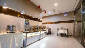 A modern hotel room with a dining area, a buffet setup, and a table with chairs. - Binle Business Express Hotel (Shijiazhuang)