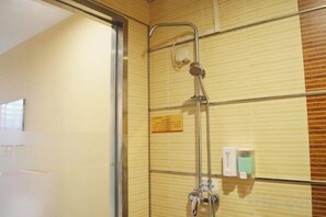 Un espace douche doté d’une porte en verre, d’un distributeur de serviettes et d’un panneau affiché sur le mur.