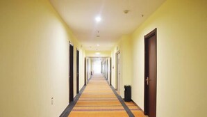 A hotel corridor with a carpeted floor, doors on both sides, and a trash bin on the right. - Binle Business Express Hotel (Shijiazhuang)