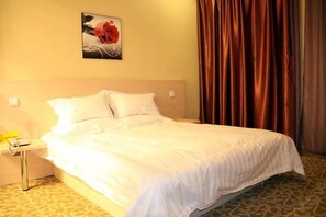Una habitación de hotel con una cama, una mesita de noche, un cuadro y una cortina.