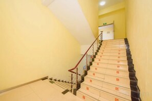 Eine Treppe mit Handlauf, Teppichstufen und einer Podestfläche mit weißer Wand und einer Tür.