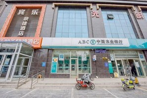 A building with a large glass facade, a sign for ABC International Agricultural Bank, and a motorcycle parked outside. - Binle Business Express Hotel (Shijiazhuang)