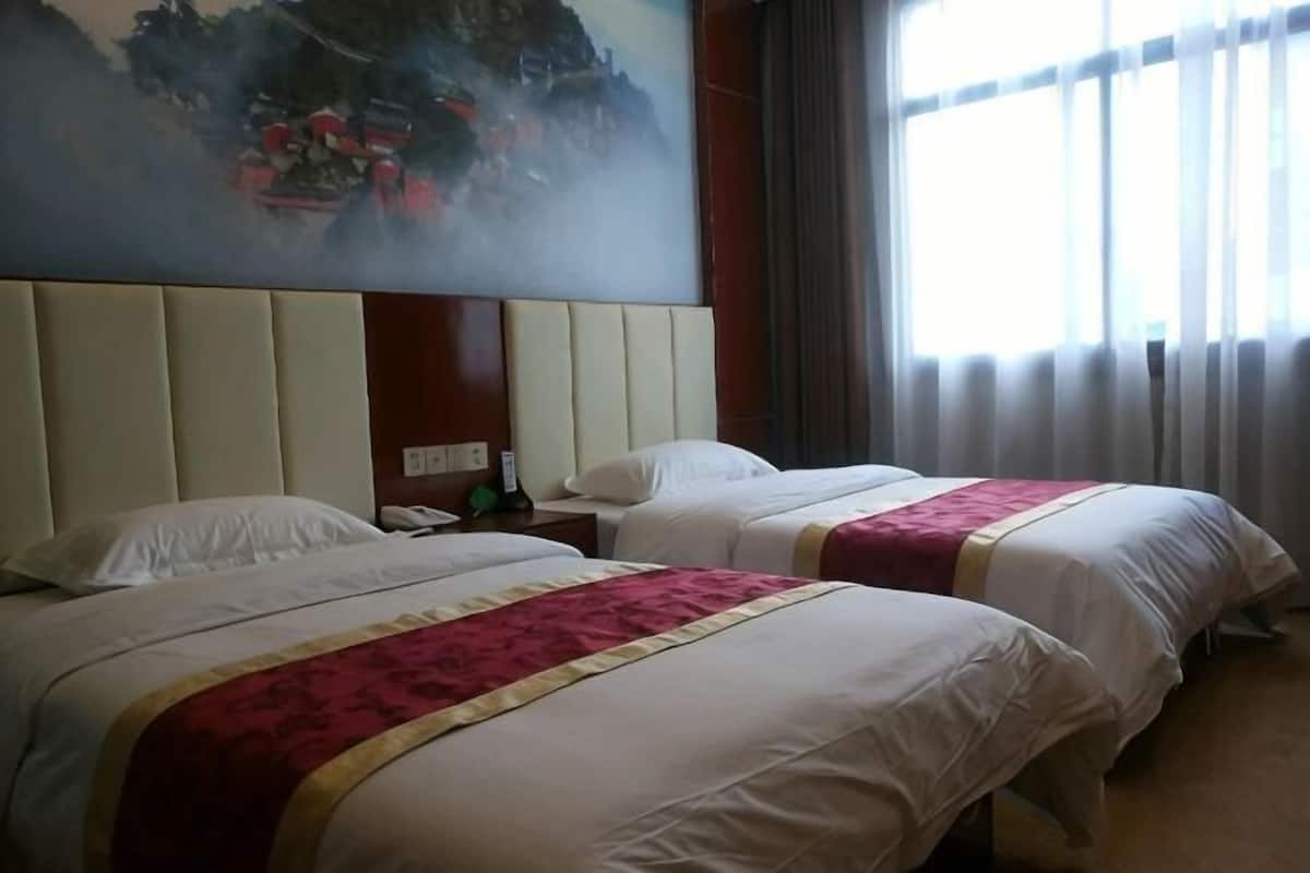 Two beds with white linens and red accents, a nightstand with a phone, and a large painting on the wall.