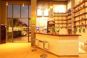 A bar area with stools, shelves with bottles, and a counter.