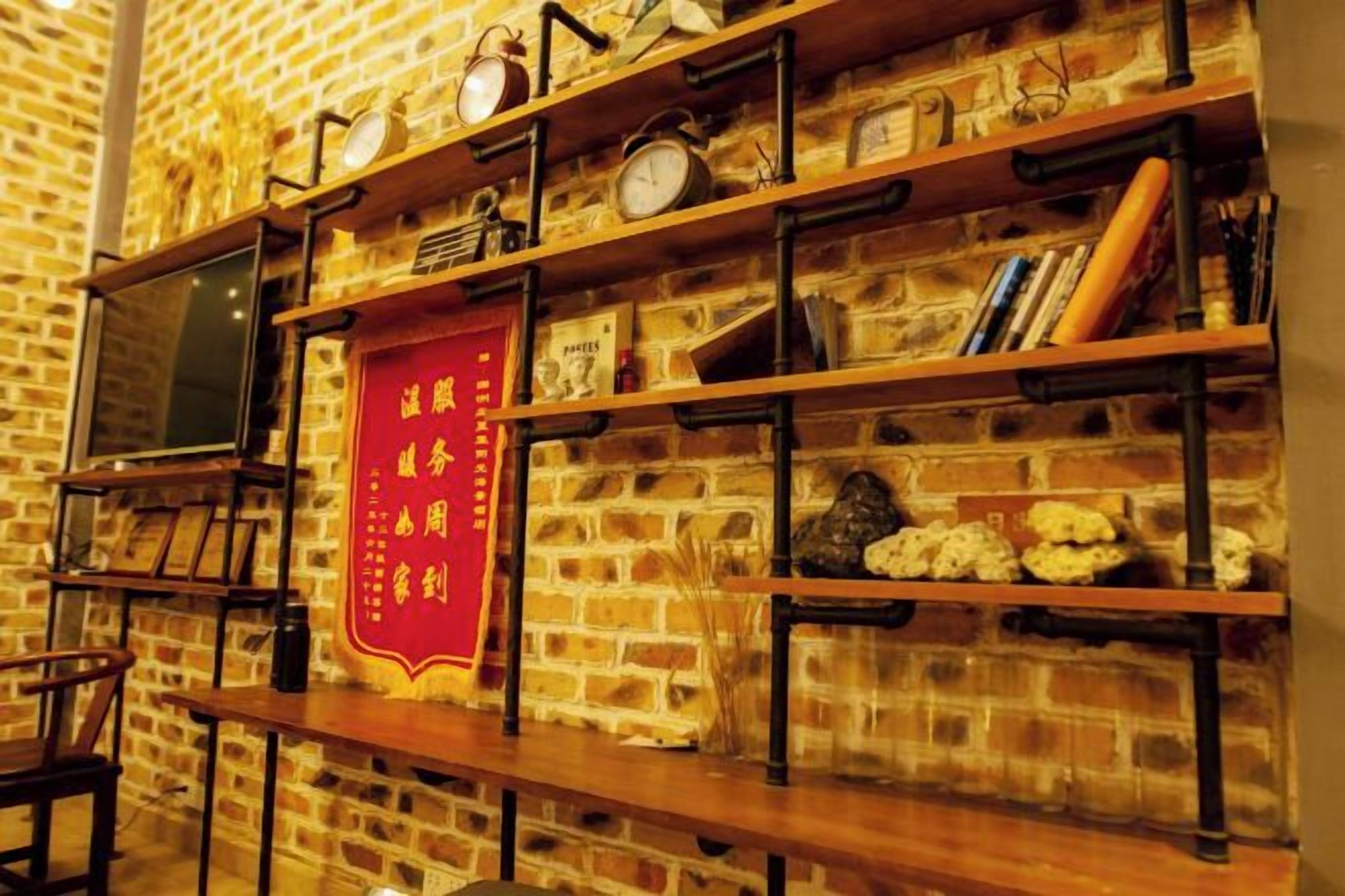 Una pared de ladrillo con estantes que sostienen relojes, libros y objetos decorativos.