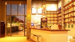 A bar area with a counter, stools, and shelves with bottles. - Weizhou Island Summer Sunshine Sea View Hotel (Weizhou Island)