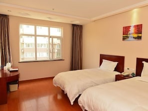 Habitación de hotel con dos camas, un escritorio, una ventana con cortinas y un cuadro en la pared.