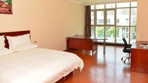 A hotel room with a large bed, a desk, and a window with a view of buildings and trees. - Greentree INN Beijing Chaoyang District Second FOR (Beijing)
