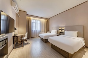 Une chambre d’hôtel avec deux lits, un bureau avec une chaise, une télévision et une fenêtre avec des rideaux.
