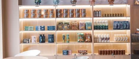 Un espacio comercial con estanterías llenas de diversos productos, una zona de estar con sillas y un armario de madera.