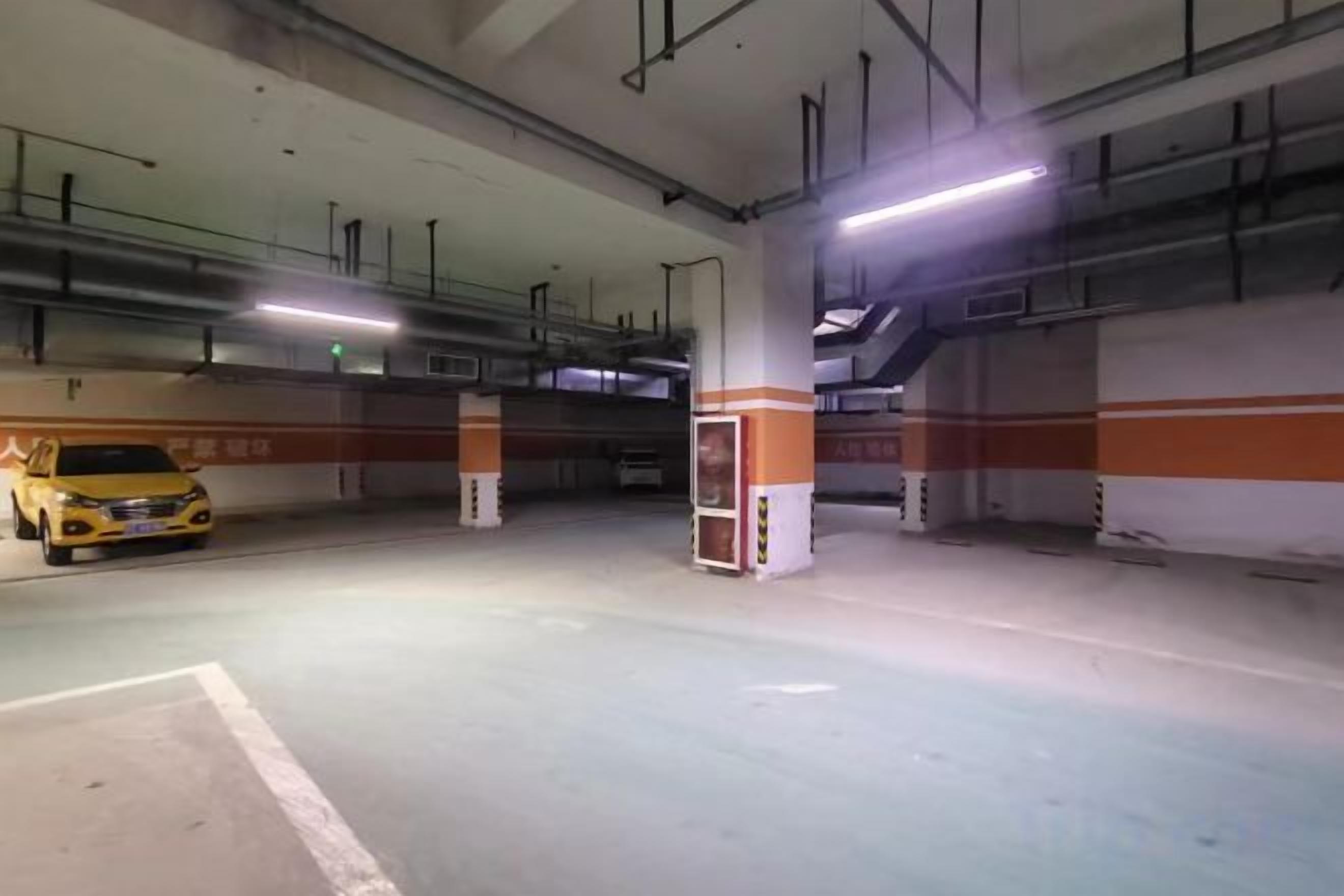 Een overdekte parkeergarage met meerdere verdiepingen, betonnen pilaren en een gele taxi geparkeerd in een van de parkeerplaatsen.