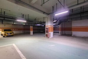 Un estacionamiento subterráneo con varios niveles, pilares de concreto y un taxi amarillo estacionado en uno de los espacios.