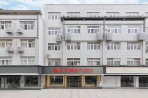 A multi-story building with a flat facade, multiple windows, and air conditioning units. - Shell Hotel (Xuzhou Xinyi Nanjing Road Railway Station) (XINYI)