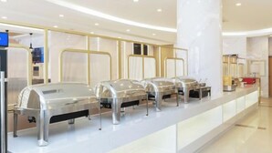 Un área de recepción moderna de hotel con un mostrador largo, varias zonas de estar y un pilar grande.