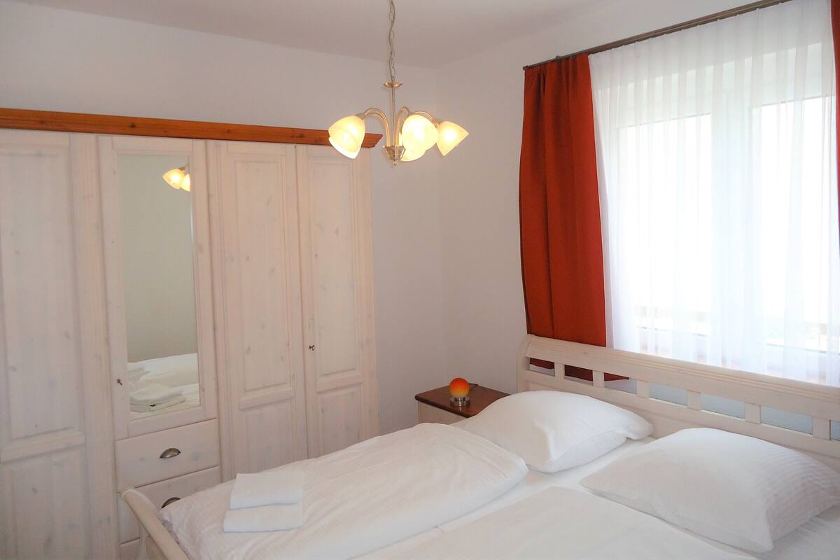 A bedroom with a bed, a nightstand, a mirror, and a wardrobe.