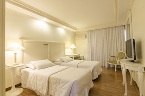 A hotel room with two beds, a TV, a desk, and a chair.