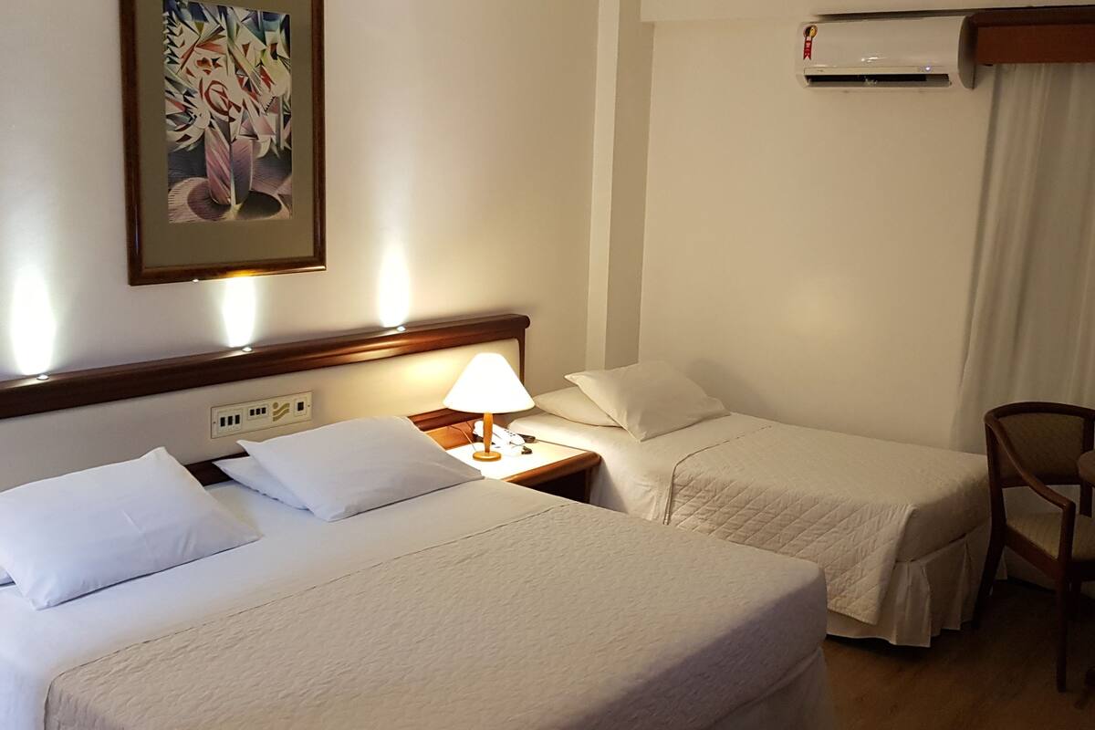 Habitación de hotel con dos camas, un escritorio, una silla y un televisor.