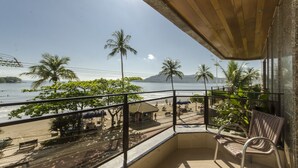 A balcony with a view of the beach and ocean, featuring a wicker chair and a small table. - Hotel Villa do Mar (Balneário Camboriú)