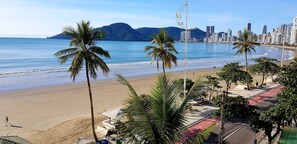 A beach with palm trees, a city skyline, and a clear sky. - Hotel Villa do Mar (Balneário Camboriú)