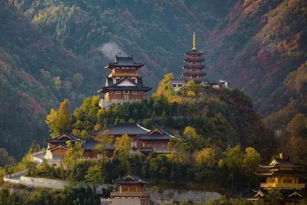 Un edificio tradicional de estilo pagoda, con varios niveles, rodeado de exuberante vegetación y colinas.