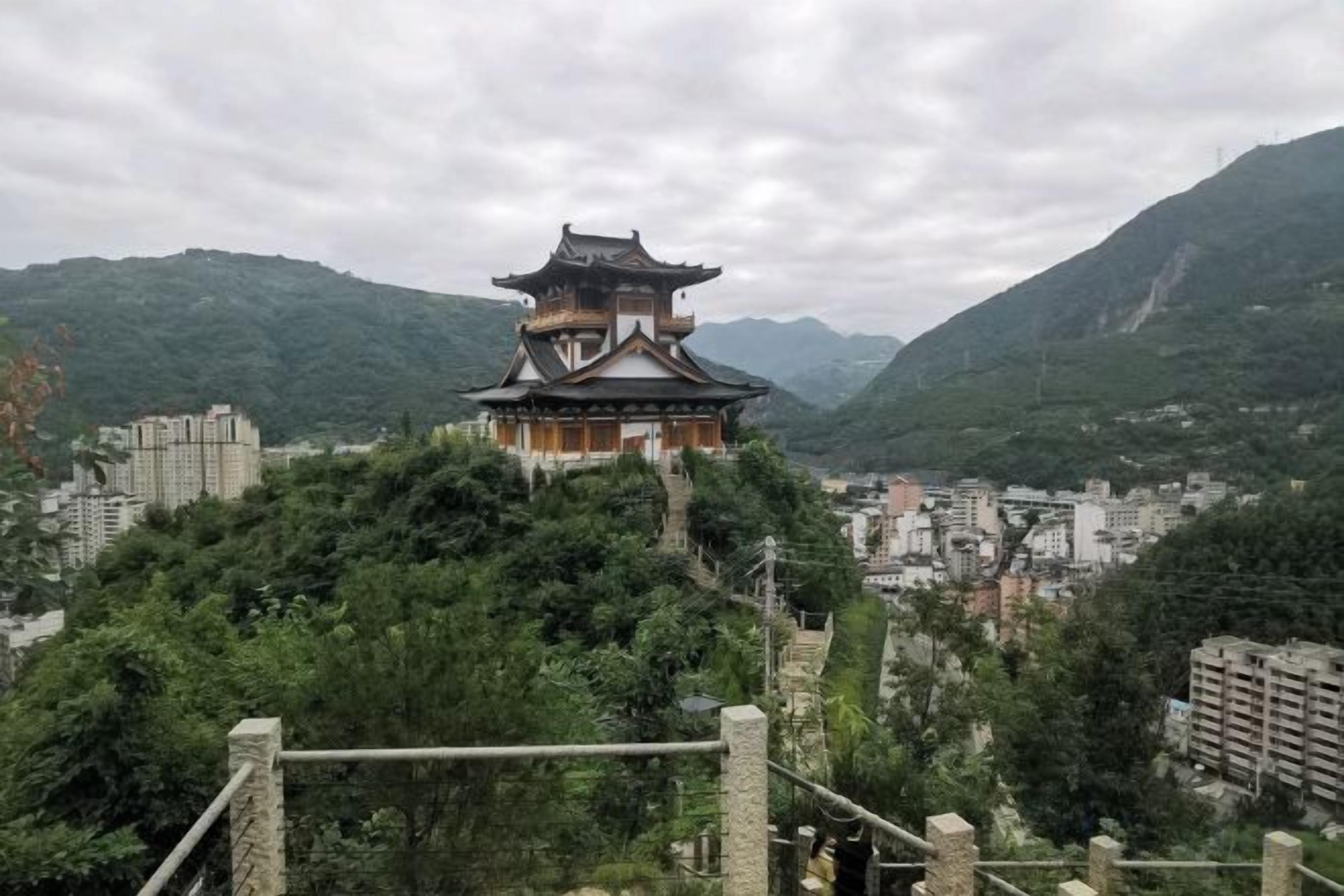 A traditional Japanese pagoda with a multi-tiered roof, surrounded by lush greenery and mountains.