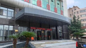 A hotel entrance with a curved facade, large windows, and a signboard. - Xinji Holiday Hotel (Nanchang)