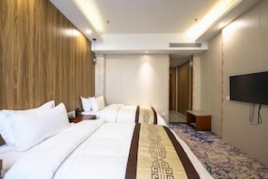 A hotel room with a large bed, a TV mounted on the wall, and a patterned carpet. - Xinji Holiday Hotel (Nanchang)