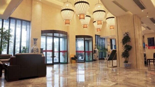 A spacious lobby with a marble floor, a reception desk, and a seating area with sofas. - Xinji Holiday Hotel (Nanchang)
