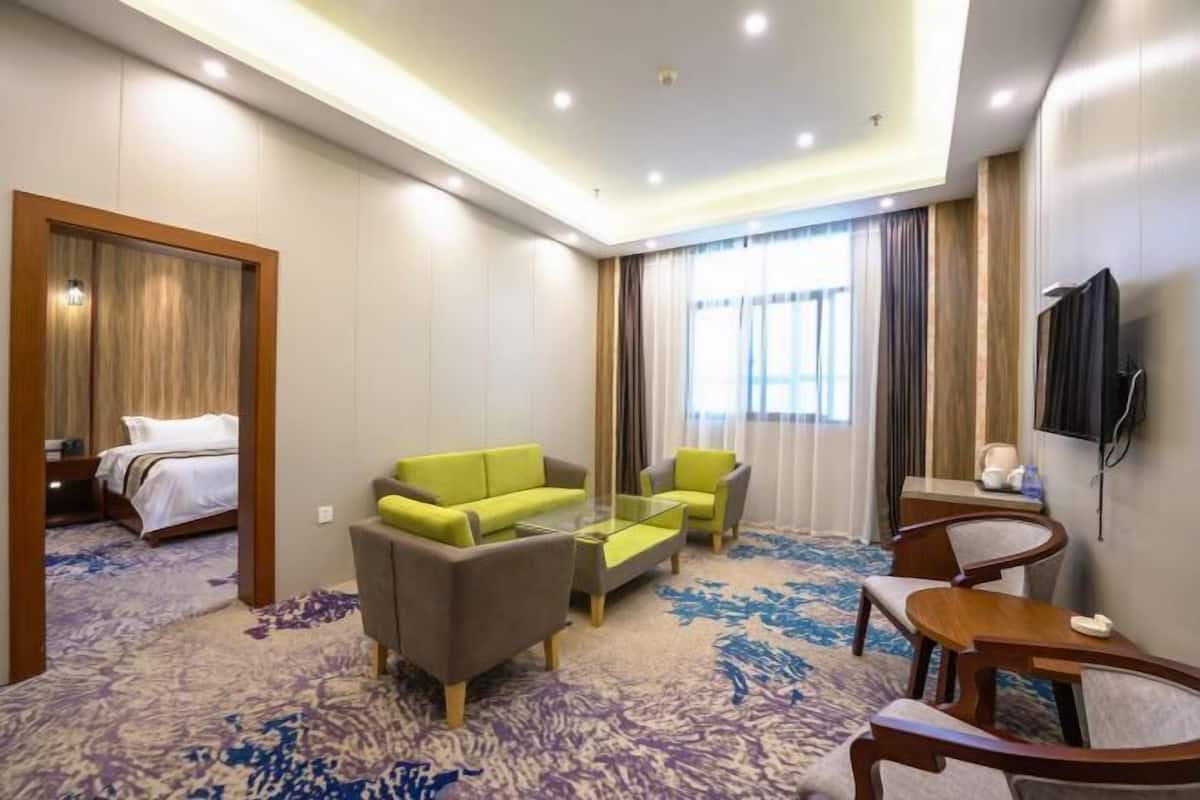 Ein Hotelzimmer mit einem Bett, einer Couch, einem Couchtisch, einem Fernseher und Teppichboden.