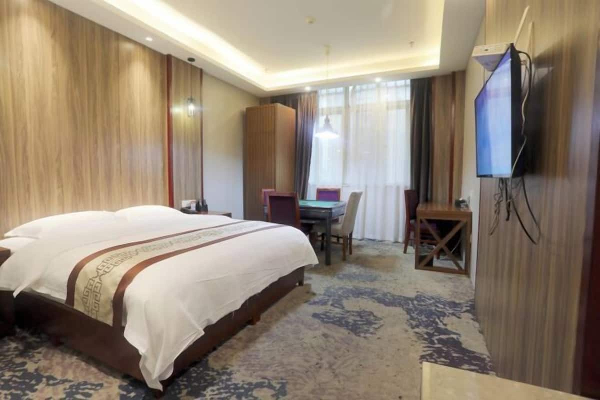 Ein Hotelzimmer mit einem großen Bett, einem Schreibtisch, einem Stuhl, einem Fernseher und einem Kleiderschrank.