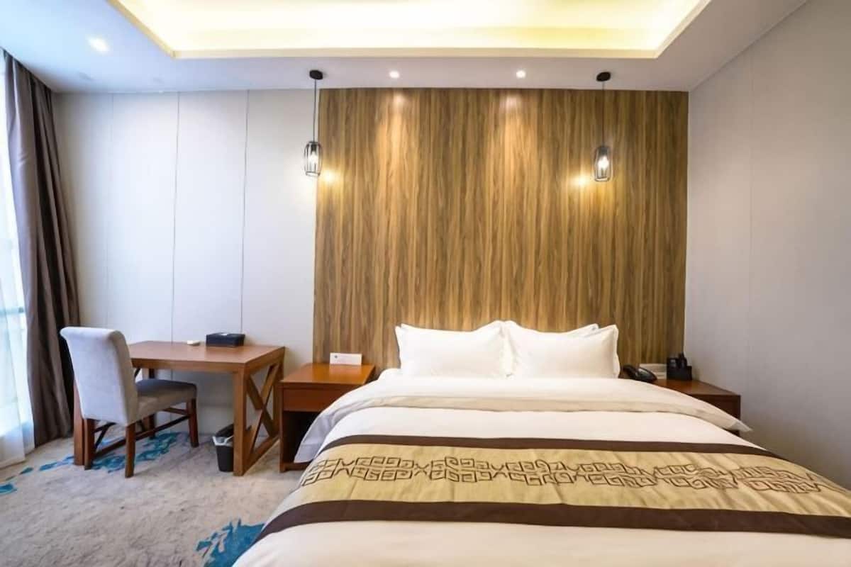 Ein Hotelzimmer mit Bett, Schreibtisch, Stuhl und einer Wand als Holzdekor.