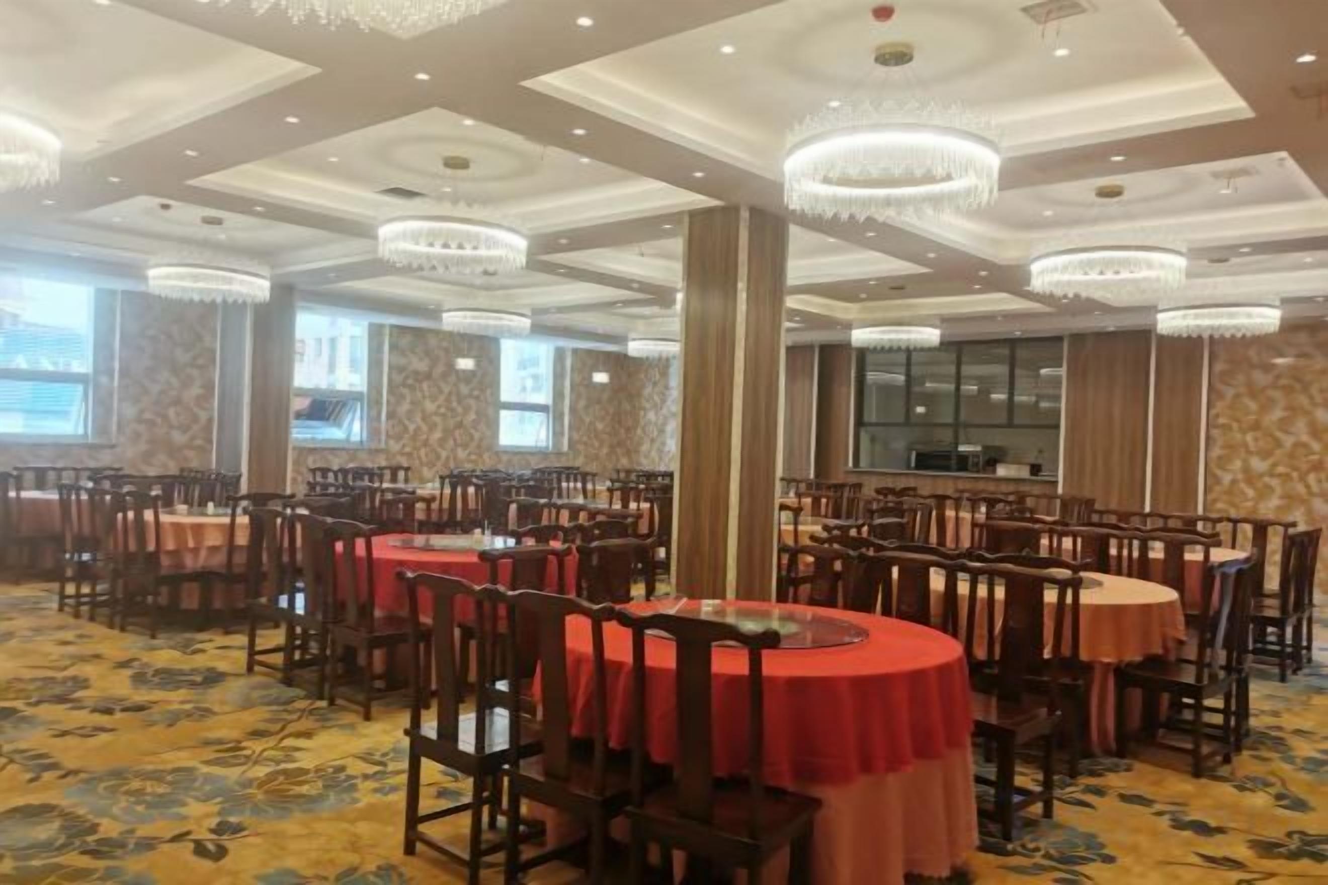 A banquet hall with round tables, chairs, and chandeliers.