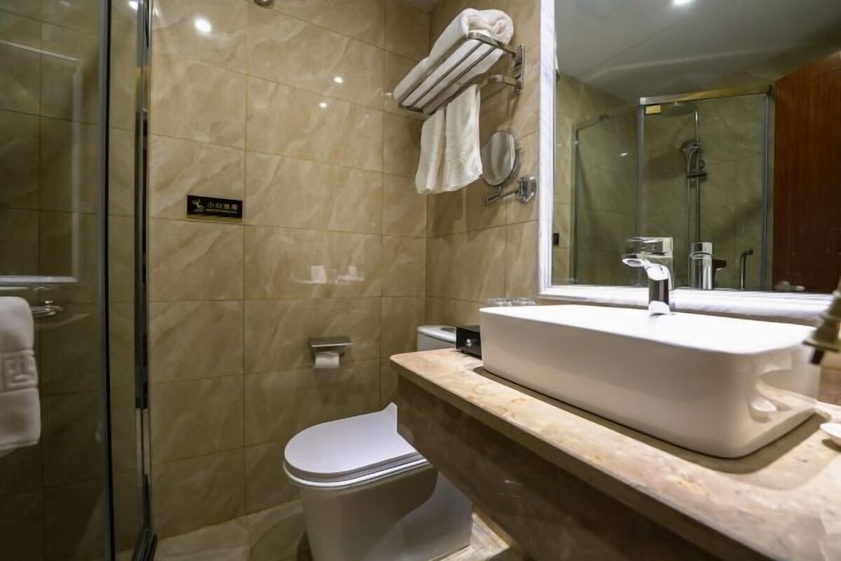 Um banheiro moderno com box de vidro, pia branca e vaso sanitário.
