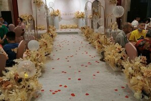 Un pasillo ceremonial adornado con flores y alfombra de pétalos rojos.