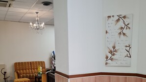 Zona de recepción con mostrador de madera, un sofá y una lámpara de araña.