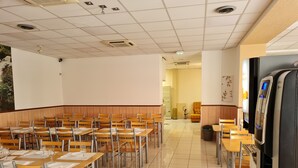 Un aula con pupitres y sillas de madera, una pantalla de proyector y una pizarra.