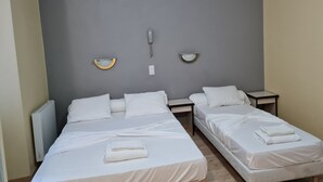 Una habitación de hotel con dos camas individuales, una mesita de noche, un teléfono en la pared y un radiador.